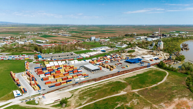 Aerial view of a bustling port filled with stacks of colorful shipping containers beside the industrial complex, Sremska Mitrovica, Vojvodina, Serbia.
