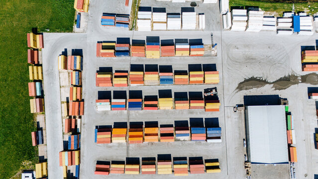 Aerial view of rows of colorful shipping containers casting strong shadows on the paved ground, creating a geometric pattern, Sremska Mitrovica, Vojvodina, Serbia.