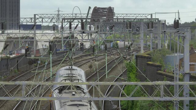 Passenger Train on Mainline Approach with HS2 Curzon Street Viaduct Construction, Birmingham, UK.
An elevated view from a bridge showing a modern passenger train navigating a curved mainline track.