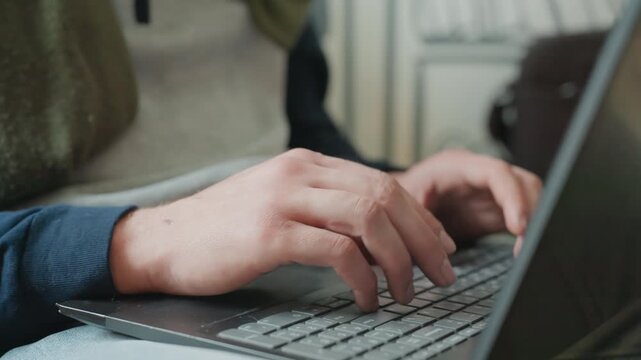 Closeup hands typing laptop keyboard freelancer in cozy apartment wearing sweater, concentrated workflow, natural light, notebook beside laptop, soft film grain, deliberate keystrokes, productive