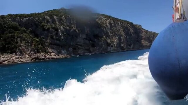 Fast moving boat on turquoise water with splashes near rocky cliffs in Orosei Sardinia Italy summer travel and sea adventure