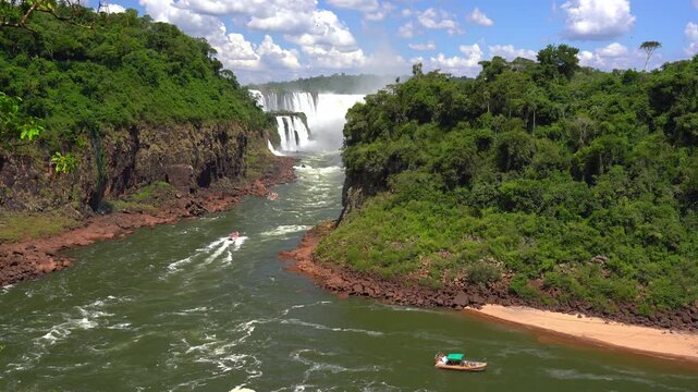 Scenic footage of Iguazu Falls in Argentina with tourist boats navigating the river through the lush tropical jungle canyon