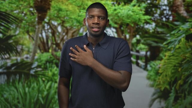 Man with hand on chest touching his heart in a forest walkway, eyes closed across frames showing smile and grimace; contemplation introspection.