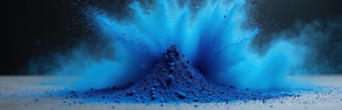 Deep blue pigment powder explodes in a vibrant cloud of cyan particles on dark background. Intense motion and abstract energy with fine dust scattering across studio floor.