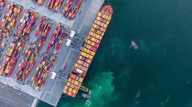 Aerial view container cargo ship at deep sea port terminal with tugboat assisting container cargo ship, Global trade and maritime supply chain, Logistics and transportation freight business industry.