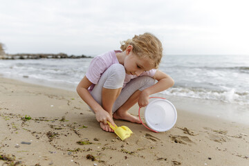 Little girl digging in sand with shovel on beach by the sea © Svetlana Iakusheva