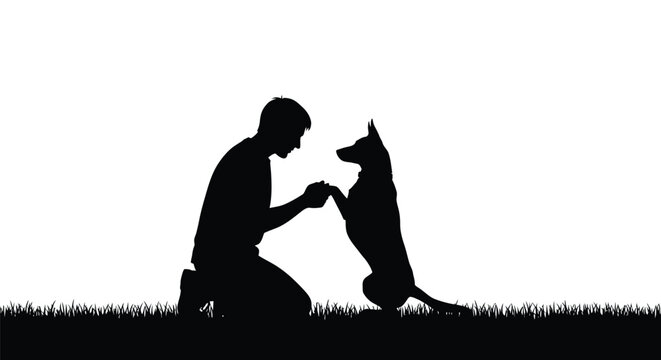 Young man kneeling on the grass and training his dog to perform a handshake trick together
