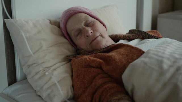 Elderly woman with IV drip lying in bed at home receiving care