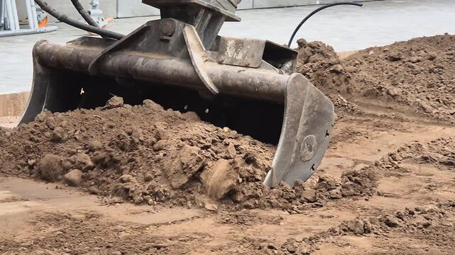 Mini excavator leveling the ground and pulling soil during garden landscape preparation.