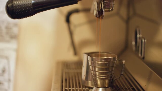 Steady pour into measuring cup. Focused home brewing with controlled pressure and transparent scale. Minimalist scene of precise espresso pouring into metal cup showing careful control and focus