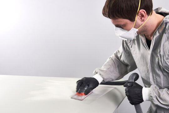 Auto mechanic wearing face mask buffing and polishing car hood in auto repair shop 