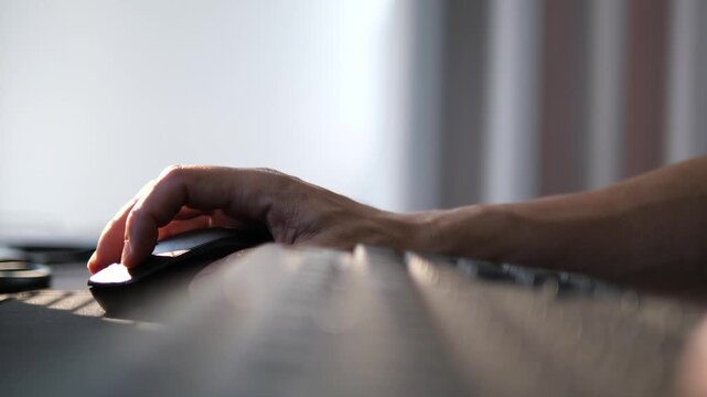 Close-up of person's hand using wireless computer mouse on desk for office work, business, and digital technology concept