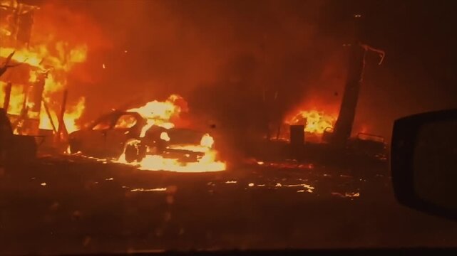 Apocalyptic scene of a car driving through a neighborhood engulfed in flames and destruction at night