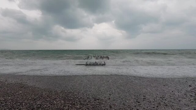 Ocean waves crashing into abandoned pier