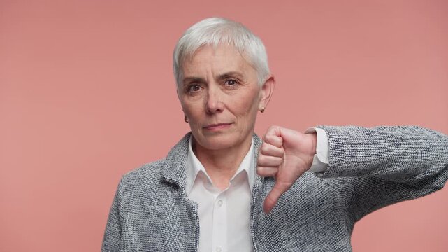 Senior woman showing thumbs down disapproval gesture