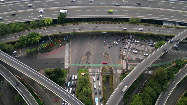 Aerial view of multilayer highway and busy intersection in Jakarta, Indonesia. Urban transport system with flyovers, cars, motorbikes, and complex road infrastructure.