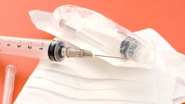 Syringe and white mask, symbols of care and prevention in a clean and impactful composition. Close-up of a syringe and white mask, essential elements in the fight against diseases