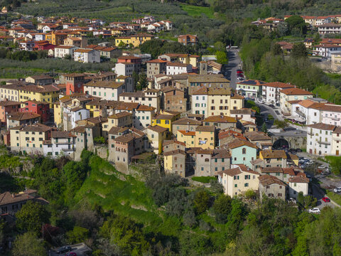 Aerial view of historic stone houses with terracotta roofs nestled on a green hillside in Loro Ciuffenna, Tuscany, Italy.