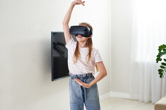 Teenage girl wearing virtual reality goggles headset and playing, vr box. technology, new generation, progress concept. Girl trying to touch objects in virtual reality.
