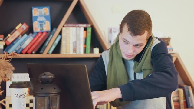 White student focused at laptop desk, cozy home library backdrop with organized bookshelf, green scarf, typing and taking notes, intent expression, warm natural light, home scholar preparing research