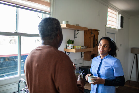 Caregiver chatting with senior in home kitchen
