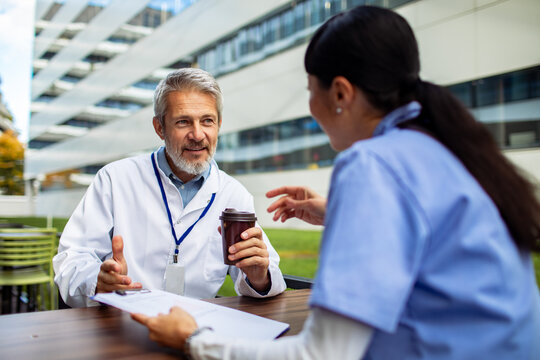 Senior doctor and nurse discussing patient notes outside hospital campus