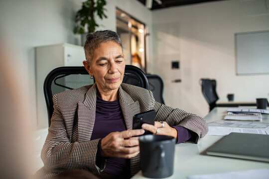 Senior businesswoman using smartphone at office desk