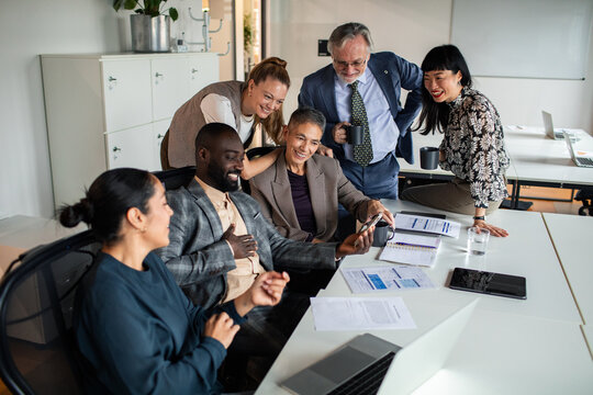 Smiling business team viewing smartphone in modern office