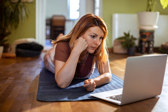 Woman watching online workout on laptop at home