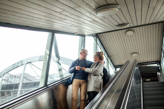 Senior couple riding escalator at modern train station