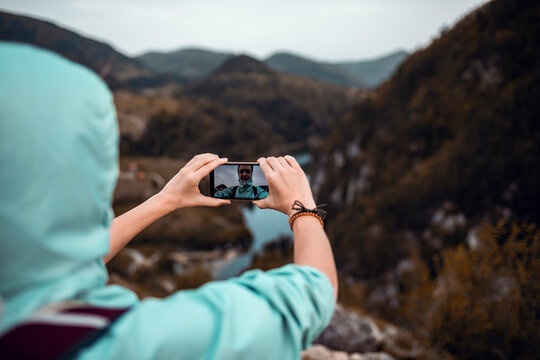 Hiker taking smartphone selfie at mountain valley viewpoint