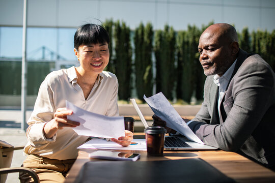 Two business colleagues reviewing documents at outdoor office table