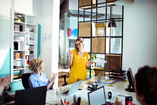 Business team applauding colleague during presentation in modern office