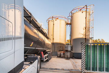 Obraz premium Tanker truck at industrial storage facility with large tanks