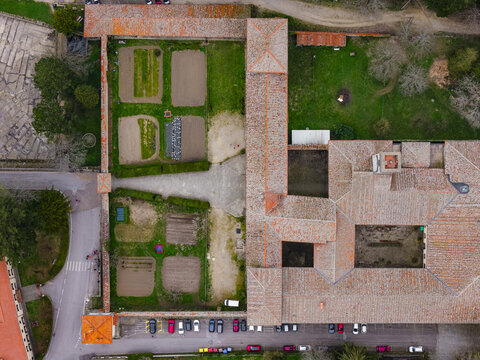 Aerial view of Vallombrosa Abbey featuring terracotta tiled roofs, internal courtyards, and green garden plots in Vallombrosa, Tuscany, Italy.