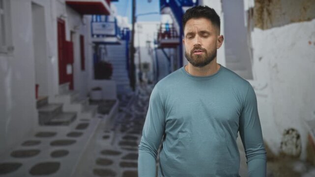 Man shrugs with palms up on a narrow street, hands spread and brows raised in a questioning gesture; uncertainty confusion.