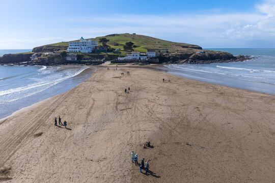 Aerial view of Burgh Island's sandy causeway emerges during low tide, a pathway to the iconic hotel under a crisp blue sky, Burgh Island, England, United Kingdom.