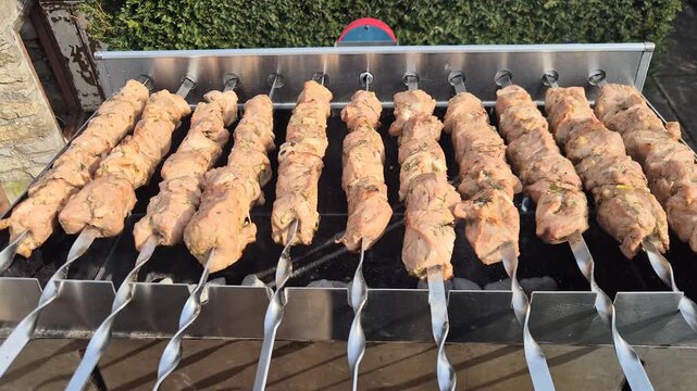 The kebabs are grilled on the coals while rotating.