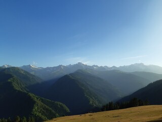 Obraz premium Scenic view of the high Caucasus mountains with lush green slopes and deep shadows during golden hour in the Svaneti region, Georgia.
