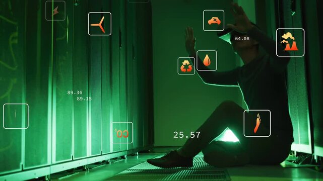 Sitting man wearing VR headset in server aisle, raising hands and using HUD icons and numbers