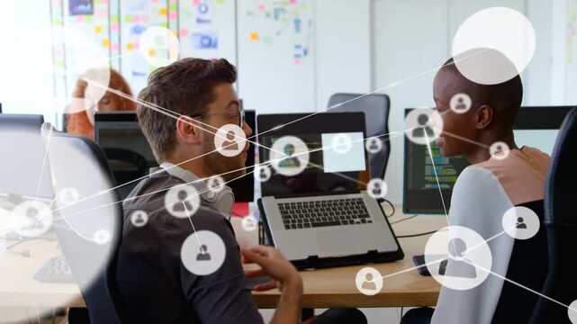 Man turning to woman, pointing at laptop and reviewing software code while network overlay growing