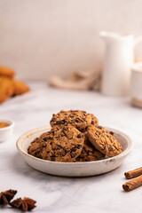 Fototapeta premium Golden chocolate chip cookies next to a glass of milk on white kitchen background. High quality photo