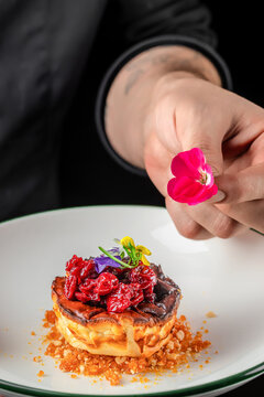 Chef decorating dessert with edible flower on gourmet plate
