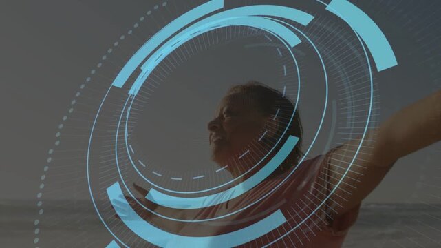 Senior woman standing shore raising arms as dotted arc sparking HUD rings over torso for healthtech