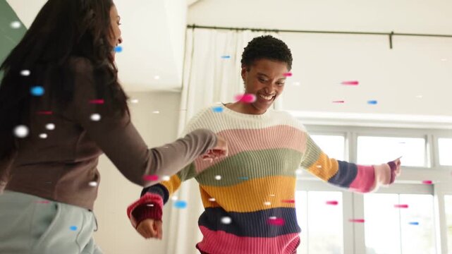 Camera pulling back revealing faces, two women dancing on bed, confetti swirling for marketing