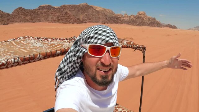 Middle-aged man wearing a keffiyeh and a young woman riding in an open-top vehicle during a desert tour in Wadi Rum, Jordan.