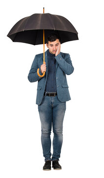 Full length portrait of upset and thoughtful businessman standing under an open umbrella, keeps palm to face looks down confused isolated on transparent background with copy space