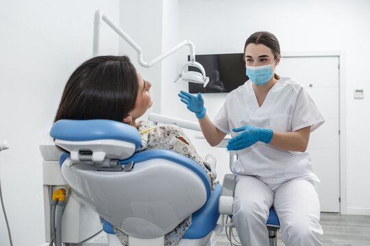 Dentist explains dental procedure to patient in modern clinic during consultation session