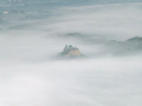 Aerial view of Le Balze del Valdarno rock formations peeking through thick morning fog and mist in Castelfranco Piandisco, Tuscany, Italy.