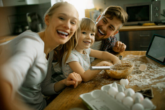 Smiling family baking together in home kitchen